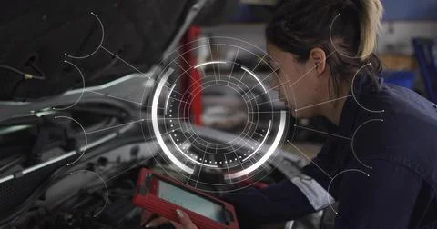 Checking tech in coverall light-patch leaning into engine bay garage holding red Stock Photos