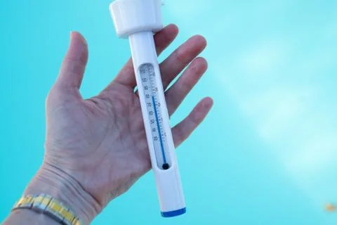 Checking the temperature of the swimming pool water with a thermometer Stock Photos