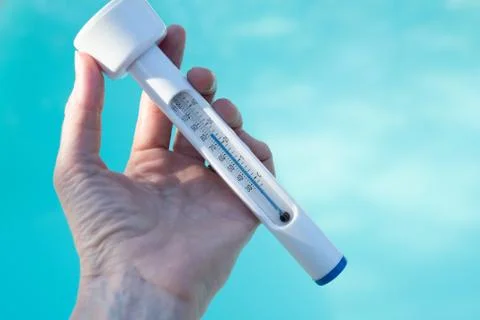 Checking the temperature of the swimming pool water with a thermometer Stock Photos