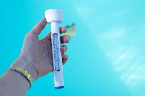 Checking the temperature of the swimming pool water with a thermometer Stock Photos