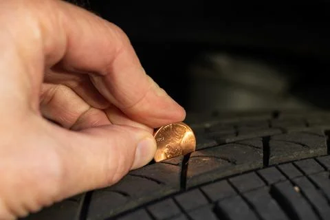 Checking tread depth on a tire by using a penny Stock Photos