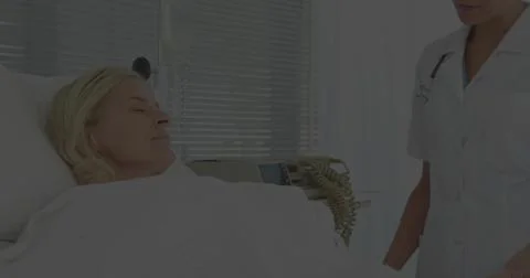 Checking uniformed nurse using stethoscope on patient in hospital room by win Stock Photos