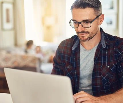 Checking the web for fun family activities. a mature man using a laptop at home 写真素材