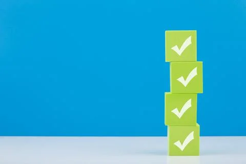 Checkmarks on four light green blocks on white table against blue background Stock Photos