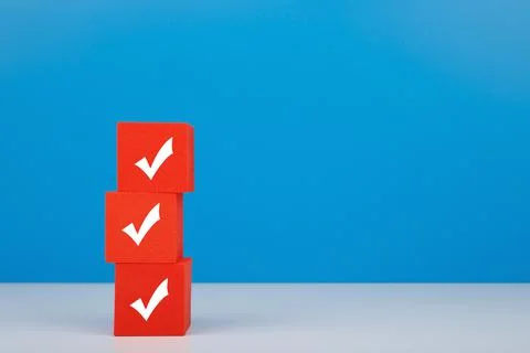 Checkmarks on three red blocks on white table against blue background with copy Stock Photos