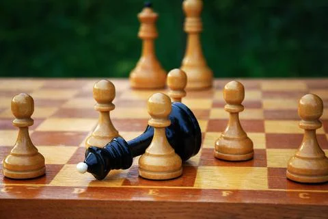 Checkmating - black chess queen fallen and surrounded by white pawns on the c Stock-Fotos