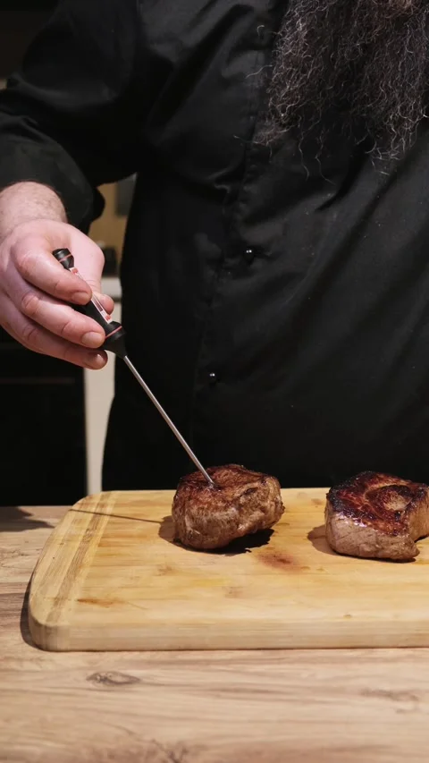 Checks the meat for doneness with a thermometer Stock Footage 305305791