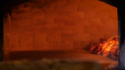 Checks pizza for readiness by pulling it out of the pizza oven using the pizza Stock Footage 127278205