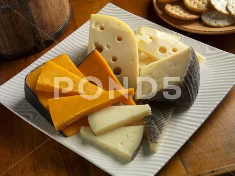 Cheddar, Baby Swiss And Manchego Cheese On A Plate; Crackers
