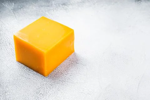 Cheddar Cheese block on a kitchen table. White background. Top view. Copy space Stock Photos
