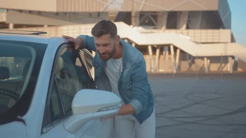 Cheeful handsome man leaning hugging the side of new modern car enjoying a Stock Footage 114250432