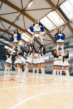 Cheerelading team divided into three groups, each doing an extension stunt Stock Photos