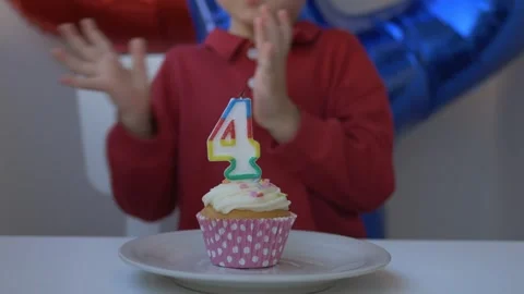 Cheerful 4-year-old boy blows out the number four candle on his birthday cupcake Stock Footage 316084644