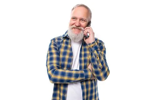 Cheerful 50s mid aged gray-haired man with a beard chatting on the phone on a Stock Photos