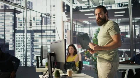 Cheerful admin holding laptop chatting with colleagues while working Stock Footage 318225859