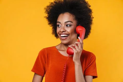 Cheerful african american girl smiling and talking on retro phone Stock Photos