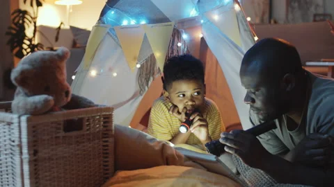 Cheerful Afro-American Dad Reading Book to Son before Bed Stock Footage 136212809