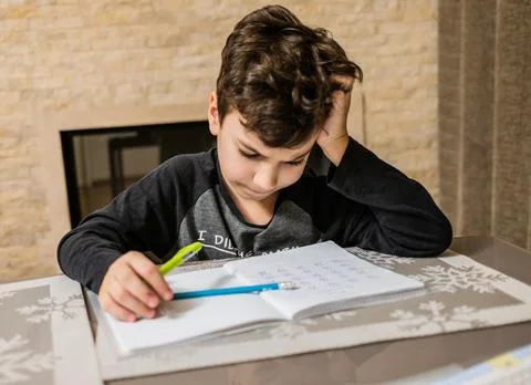 Cheerful and funny schoolboy solves his homework emotionally. Thinks about how Фото