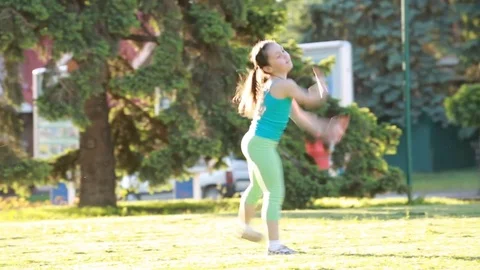 Cheerful and happy little girl dancing and playing on green grass in the park. Stock Footage 75869776