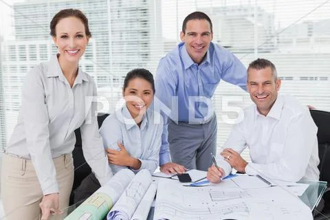 Cheerful architects posing while anaylzing plans together Stock Photos