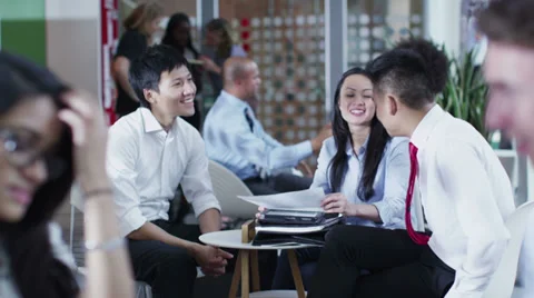 Cheerful Asian business group in informal meeting in office cafe area Stock Footage