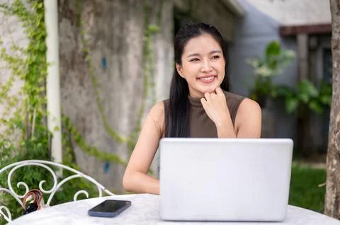 Cheerful Asian Freelancer Thinking In Front Of Laptop Outdoors Stock Photos