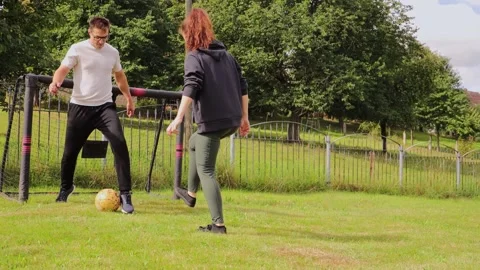 In a cheerful backyard setting, a couple engages in a friendly soccer match Stock Footage 317034603