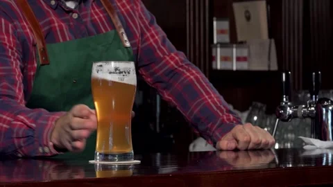 Cheerful bartender serving a refreshing glass of craft beer on the counter Stock Footage 311202081