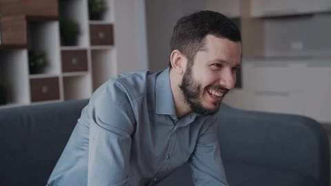 Cheerful beard man is sitting on coach and very emotional playing in video game. Video stock 108315280