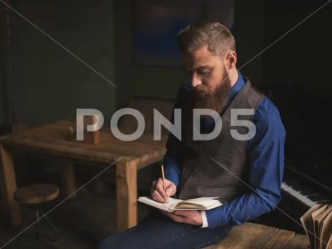 Cheerful bearded author is writing a poem Stock Photos