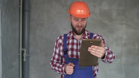Cheerful bearded builder or foreman has video call while working at construction Stock Footage 220113373