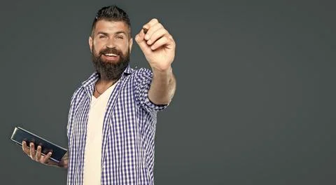 Cheerful bearded man making notes in book point on you Stock Photos