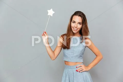 Cheerful beautiful young woman holding magic wand Stock Photos