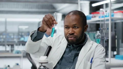 Cheerful biochemist in lab evaluates compound solutions for new drug formulation Stock Footage 327416881