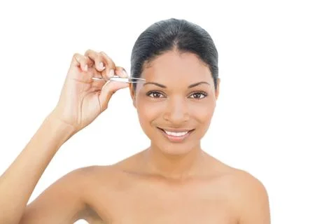 Cheerful black haired model removing hairs from her eyebrow 스톡 사진