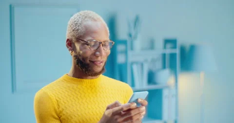 Cheerful black man in glasses using mobile phone chatting online on social media Stock Footage 163146082