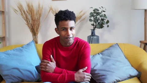 Cheerful black man sitting on sofa Stock Footage 230140581