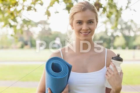 Cheerful blonde woman posing holding an exercise mat Stock Photos