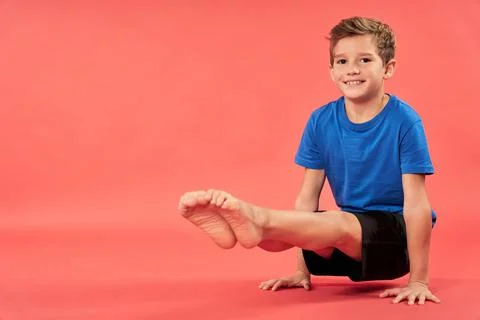 Cheerful boy doing exercise against red background Stock Photos