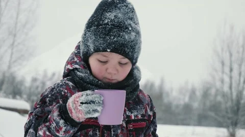 Cheerful boy drinking hot tea from cup in snowy forest at winter walk. Boy Stock Footage 146646331