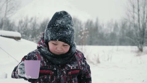 Cheerful boy drinking hot tea from cup in snowy forest at winter walk. Boy Stock Footage 148268060