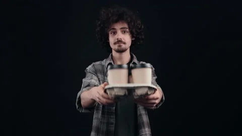 The cheerful boy, filled with four coffees in his hand, sits and spreads the Stock Footage 155210580