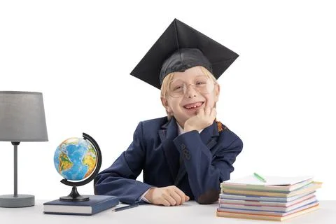 Cheerful boy first grader in students hat and large glasses next to notebooks 스톡 사진