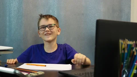 A cheerful boy with glasses sitting at the table laughs a lot and makes fun Stock Footage 144935031