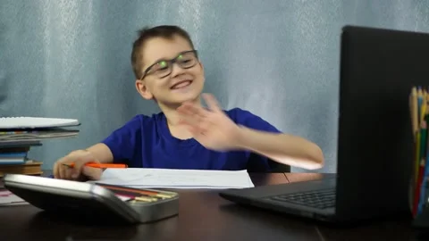 Cheerful boy with glasses sitting at the table tells about the test. remote Stock Footage 145145166