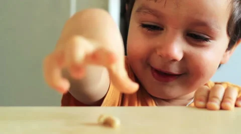 A cheerful boy is having fun. He is smiling, giggling and playing with a nut Video stock 57472293