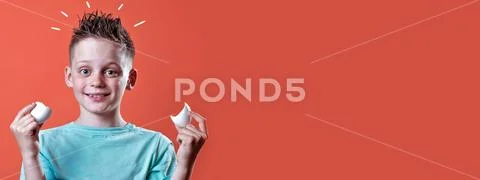 Cheerful boy in a light t-shirt holding a broken egg on a colored background Stock Photos