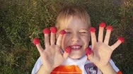 Cheerful Boy Lying On The Grass With Raspberries Dressed On His Fingers Laughing Stock Footage