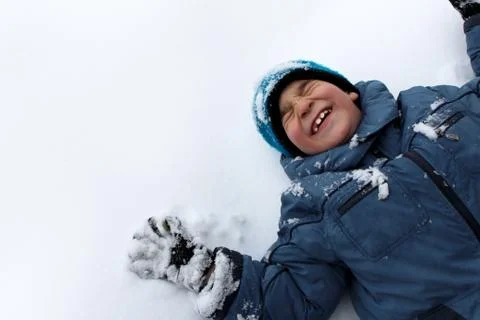 Cheerful boy lying on the snow. Stock Photos