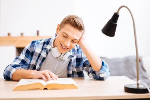 Cheerful boy reading a book at the table Stock Photos
